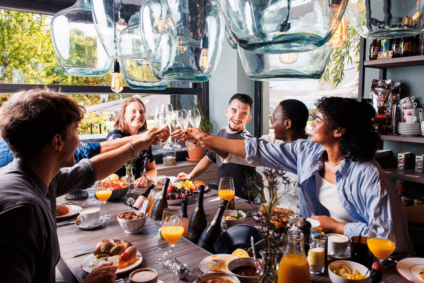 Junge Menschen stoßen in einem Lokal an, gedeckter Tisch Foto: Adrian Almasan