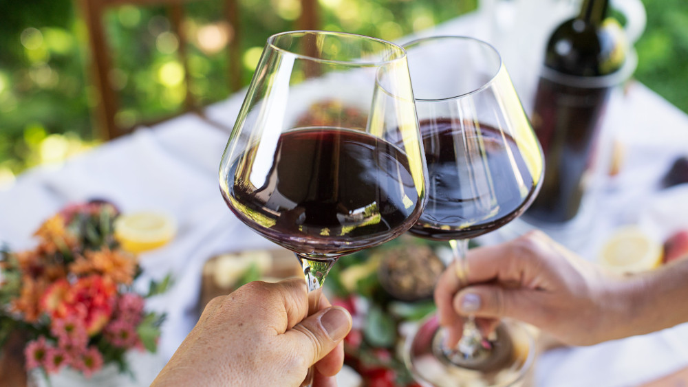 Zwei Gläser Rotwein werden im Garten angestoßen. © ÖWM / Carletto